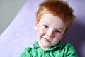 Closeup portrait of a cute red haired freckled little boy in green t-shirt waiting for doctor in medical office Royalty Free Stock Photo