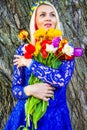 Closeup Portrait of Cute and Sensual Romantic Caucasian Blond Girl with Bunch of Tulips Posing Outdoors Royalty Free Stock Photo