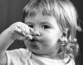 Closeup portrait of cute small baby boy eating healthy food of porridge from plate with spoon in hand. Royalty Free Stock Photo