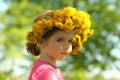 Close up portrait of a cute two years old girl wearing a dandelion wreath, glance over shoulder