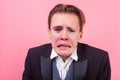 Closeup portrait of desperate man in suit crying. indoor studio shot isolated on pink background