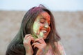 Closeup portrait of emotional brunette woman celebrating Holi colors festival at the desert