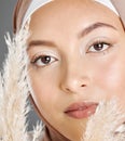 Closeup portrait face of beautiful young muslim woman wearing natural makeup and headscarf posing with pampas wheat Royalty Free Stock Photo