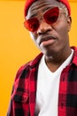 Closeup portrait of a fashionable black man African in red retro glasses and a plaid shirt and hat in the studio Royalty Free Stock Photo