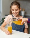 Closeup portrait of a female hand pours cute little girl orange juice. Royalty Free Stock Photo