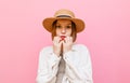 Closeup portrait of frightened girl in hat and summer clothes on pink background looking into camera with shocked face. Portrait