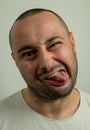 Closeup portrait of funny angry young bully man sticking his tongue out at you camera gesture, isolated on white Royalty Free Stock Photo