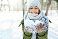 Closeup portrait of funny smiling woman in woolen hat and long warm scarf holding snow to the camera at snowy winter Royalty Free Stock Photo