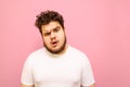 Closeup portrait of a funny surprised fat man with beard and curly hair on a pink background, looks into the camera with a look of Royalty Free Stock Photo