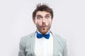 Closeup portrait of funny surprised handsome bearded man in casual grey suit, blue bow tie standing and looking at camera with big Royalty Free Stock Photo