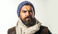 Closeup portrait of handsome bearded man in leather jacket, woolen scarf and knitted hat. Serious stylish guy in autumn Royalty Free Stock Photo