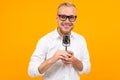 Closeup portrait of a handsome man in a white shirt with a retro speaking microphone on a yellow background Royalty Free Stock Photo