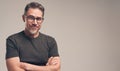 Closeup portrait of handsome middle aged man with folded arms, wearing eyeglasses, standing on white grey background, looking at Royalty Free Stock Photo