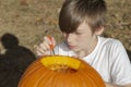 Closeup portrait of a young boy outside carving pumpkin Royalty Free Stock Photo