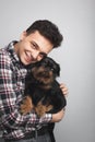 Closeup portrait handsome young hipster man, kissing his good friend black dog isolated light background. Positive human emotions,