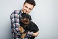 Closeup portrait handsome young hipster man, kissing his good friend black dog isolated light background. Positive human emotions,