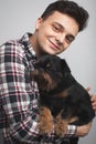 Closeup portrait handsome young hipster man, kissing his good friend black dog isolated light background. Positive human emotions,