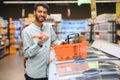 Closeup portrait, handsome young man picking up bell peppers, choosing yellow and orange vegetables in grocery store Royalty Free Stock Photo