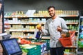 Closeup portrait, handsome young man picking up bell peppers, choosing yellow and orange vegetables in grocery store Royalty Free Stock Photo