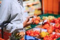 Closeup portrait, handsome young man picking up bell peppers, choosing yellow and orange vegetables in grocery store Royalty Free Stock Photo