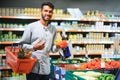 Closeup portrait, handsome young man picking up bell peppers, choosing yellow and orange vegetables in grocery store Royalty Free Stock Photo