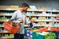 Closeup portrait, handsome young man picking up bell peppers, choosing yellow and orange vegetables in grocery store Royalty Free Stock Photo