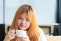 Closeup portrait of happy beautiful woman with blonde red hair and white shirt is smiling and holding white cup coffee and looking Royalty Free Stock Photo