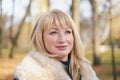 Closeup portrait of happy blonde mature woman is standing in autumn park and thinking. Beautiful woman is relaxing in nature on Royalty Free Stock Photo