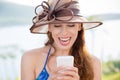 Closeup portrait happy excited young girl in hat looking at phone with toothy smile laugh seeing funny news photos isolated