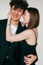 Closeup portrait of happy loving couple in black outfits for event, gray studio background. Smiling guy and elegant girl Royalty Free Stock Photo