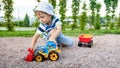 Closeup portrait of happy smiling 3 years old child boy digging sand on the playground with toy plastic truck or Royalty Free Stock Photo