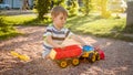 Closeup portrait of happy smiling 3 years old child boy digging sand on the playground with toy plastic truck or Royalty Free Stock Photo