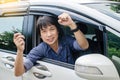 Closeup portrait happy, smiling, young asian man, buyer sitting in his new a car showing car key ,the concept of buying a used car Royalty Free Stock Photo