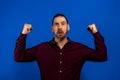 Closeup portrait happy successful student, business man winning, fists pumped celebrating success  blue wall Royalty Free Stock Photo