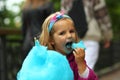 Closeup portrait of happy toddler girl eating blue cotton candy