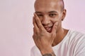 Closeup portrait of happy young mixed race tattooed man in white t shirt smiling at camera, touching his face, posing Royalty Free Stock Photo