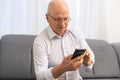 Closeup portrait headshot elderly man with glasses having seeing cell phone has vision problems. Royalty Free Stock Photo