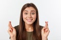 Closeup portrait hopeful beautiful woman crossing her fingers, open eyes, hoping, asking best isolated on gray wall