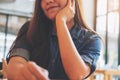 Closeup portrait image of beautiful Asian woman with smiley face and feeling good sitting in cafe with green nature Royalty Free Stock Photo