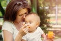Closeup portrait of a infant baby eating vegetable puree from spoon. Mother feeding little child outdoor on a walk in summer day Royalty Free Stock Photo