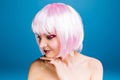 Closeup portrait joyful young woman with naked shoulders, pink haircut smiling to side on blue background. Brightful Royalty Free Stock Photo