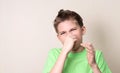 Closeup portrait kid pinches nose with fingers hands looks with Royalty Free Stock Photo