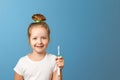 Closeup portrait of a little girl on a blue background. A child holds a toothbrush. The concept of daily hygiene.