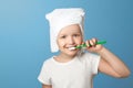 Closeup portrait of a little girl on a blue background. A child with a white towel on his head brushing his teeth. Royalty Free Stock Photo