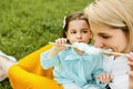Closeup portrait of little girl eating cotton candy with her mom, sitting on the green grass in the park. Mothers day. Royalty Free Stock Photo