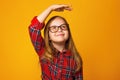 Closeup portrait of a little girl on a yellow background. A child with glasses measures his height Royalty Free Stock Photo