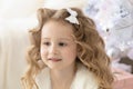 Little toddler pensive smiling blonde girl with long hair near christmas tree on new year Royalty Free Stock Photo