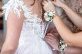 Closeup portrait of a maid of honor helping the bride with her dress. happy young bride getting ready, wedding photohappy young