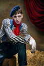 Closeup portrait of male mime artist expressing sadness and loneliness over dark retro circus backstage background Royalty Free Stock Photo