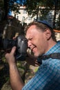 Closeup portrait of a male tourist photographer with a jewish hat holding a camera taking a shot.